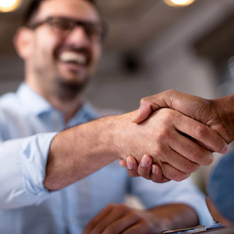 Two people shaking hands, with picture focusing on handshake