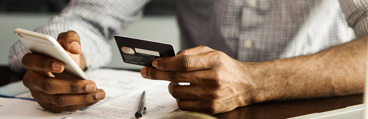 Man using his smart phone and debit card to pay his health insurance bills.