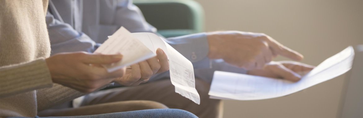 Closeup of two peoples' hands as they review receipts and a Medicare Summary Notice.