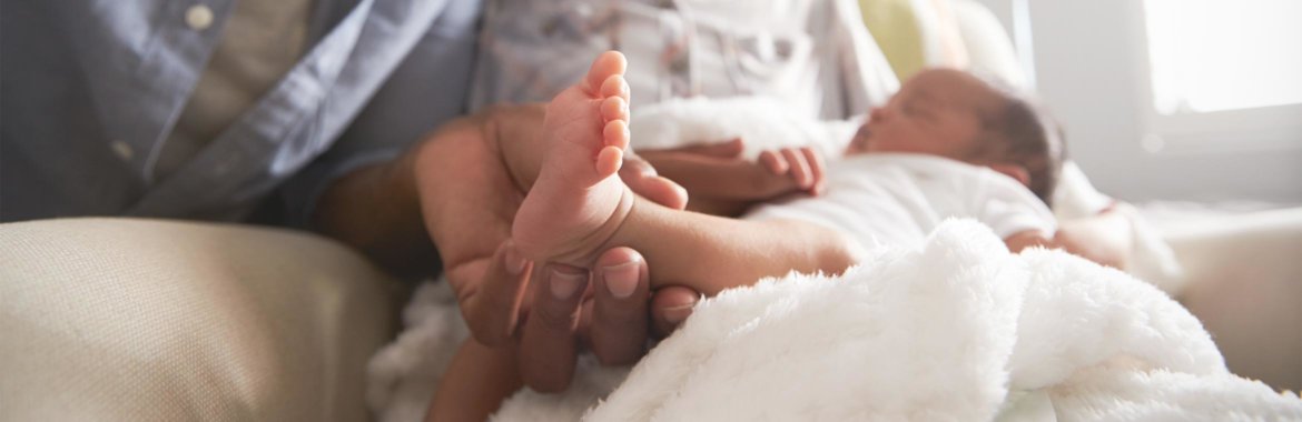 Close up of father holding newborn baby's feet.