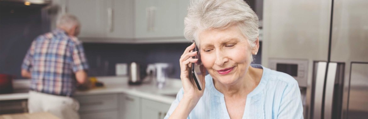 Elderly woman discusses Medicare enrollment options over the phone.
