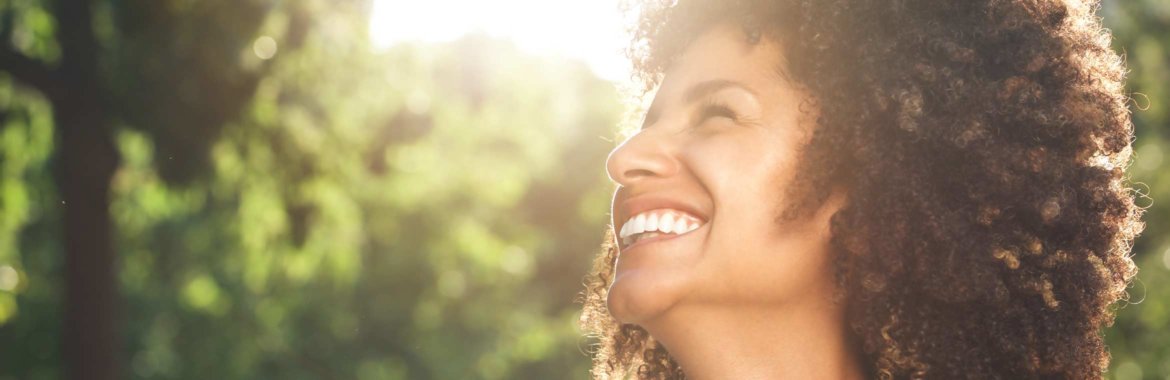 Closeup of African American woman smiling in the sunlight.