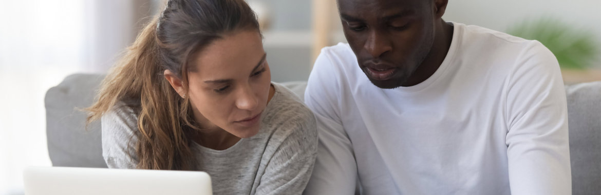 Young interracial couple reviews family health insurance plans.