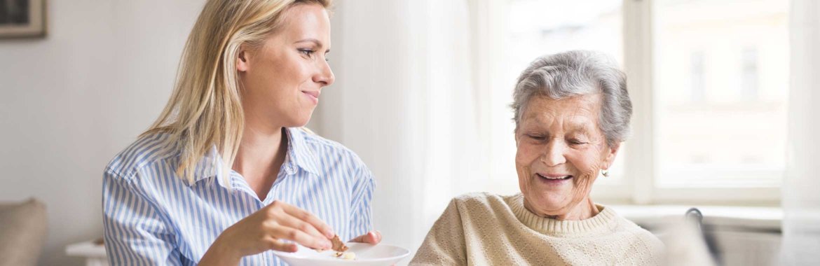 Elderly woman and her caregiver enjoy a meal together.