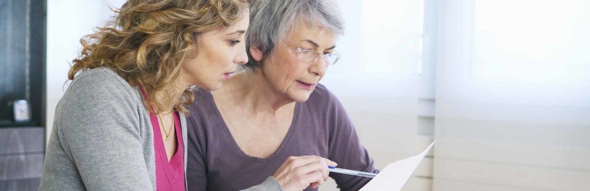 Elderly woman reviews Medicare options with her caregiver.