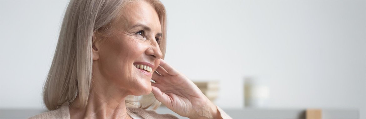 An older woman smiles while thinking about something.