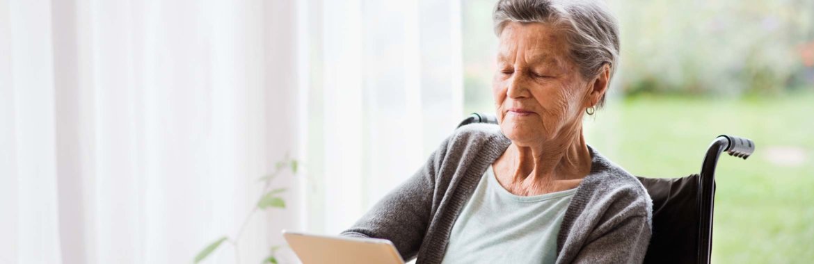Elderly woman in a wheelchair reviews her Medicare options on a tablet.