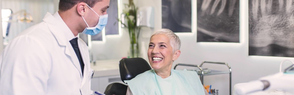A senior woman discusses dentures with her dentist.