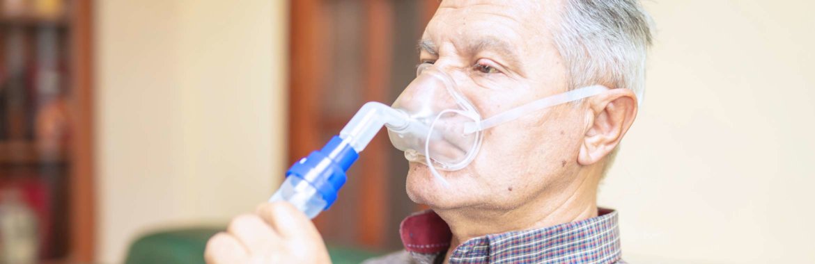A senior man uses a nebulizer covered by Medicare.