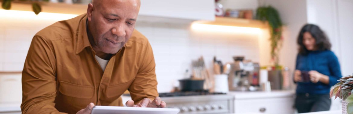 Man enrolls in Medicare on a tablet in his kitchen.