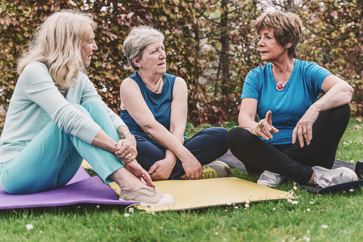 Women on yoga mats talking.