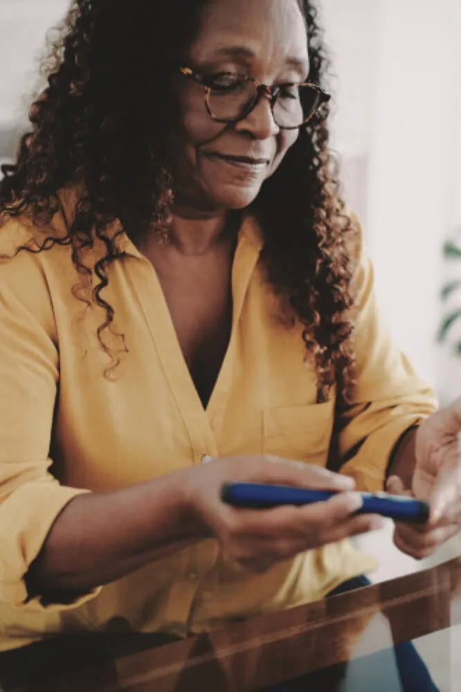 A woman is holding a glucose meter and checking her blood sugar level