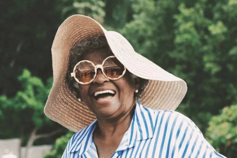 Smiling woman with large straw sunhat and round glasses