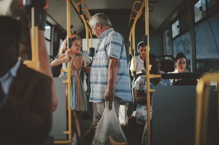 A senior man and a girl are standing on the bus