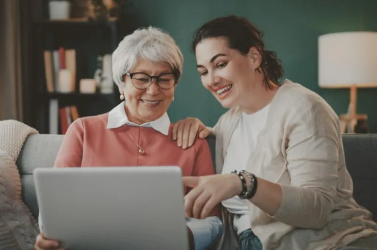 A senior mom and her adult daughter reviewing something on a laptop