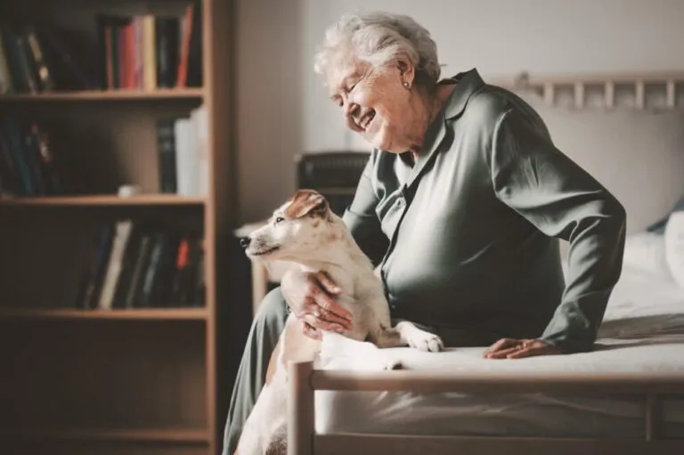 A senior woman sitting on her bed with her dog by her side