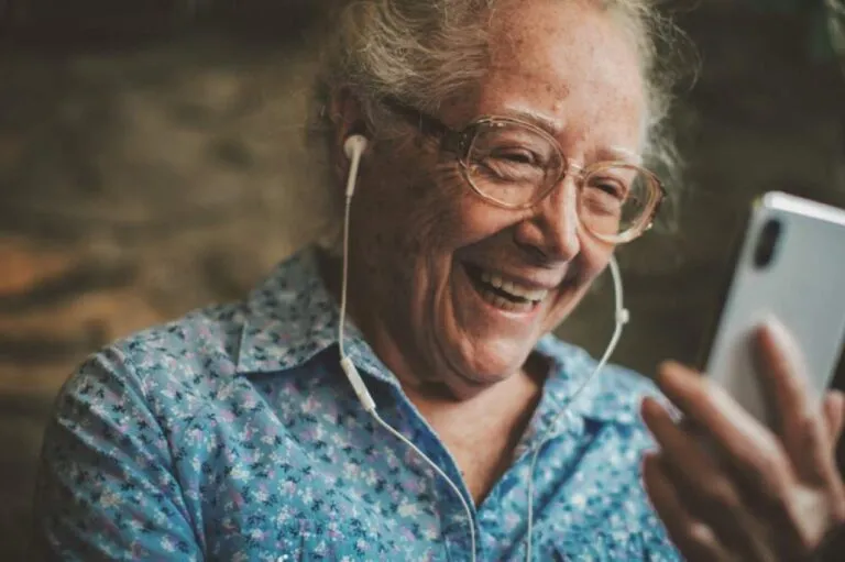 A senior woman wearing earbuds is having a video call