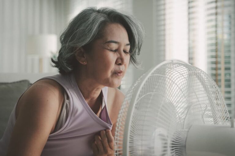 Woman cooling herself with electric fan.