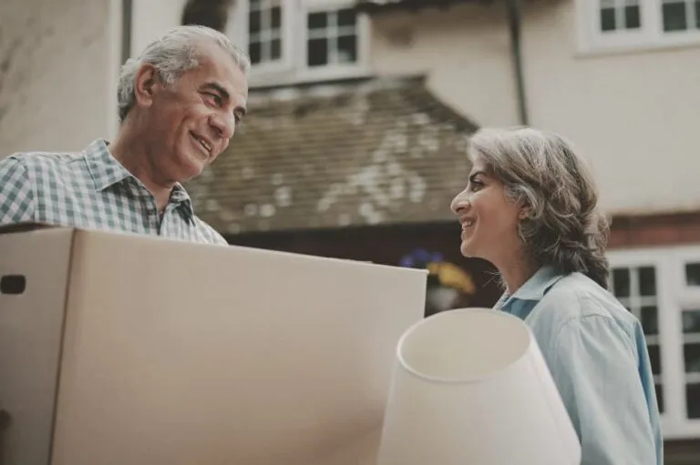 Couple holding a moving box and a lamp.