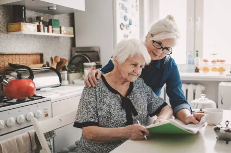 A senior woman with her adult daughter looking at a notebook