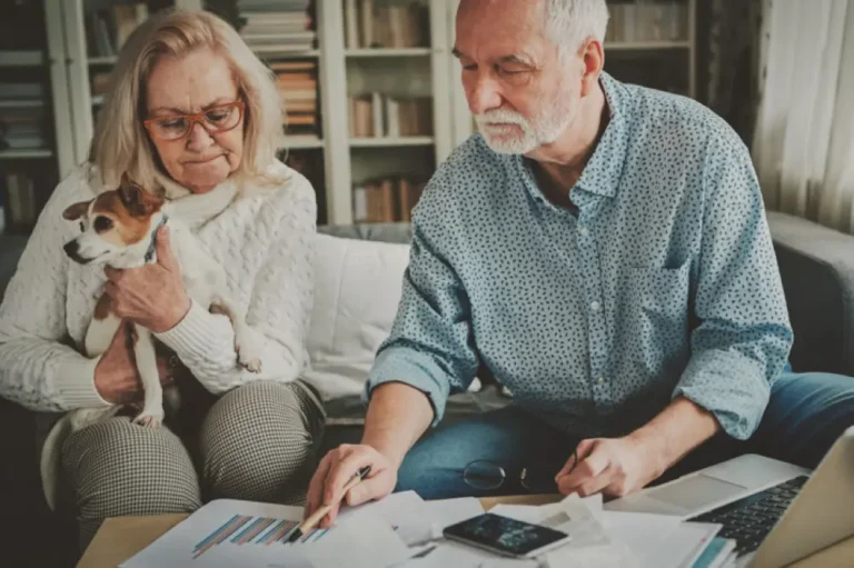 Couple sitting on couch with a small dog, discussing funeral expense insurance options.