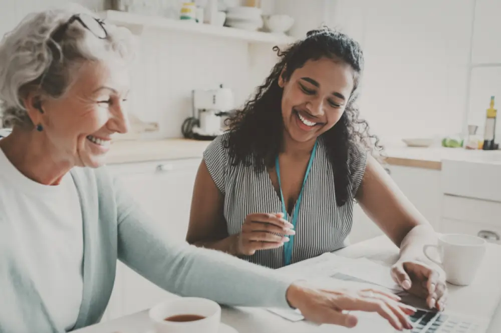 Younger woman sitting beside an older woman at a computer.